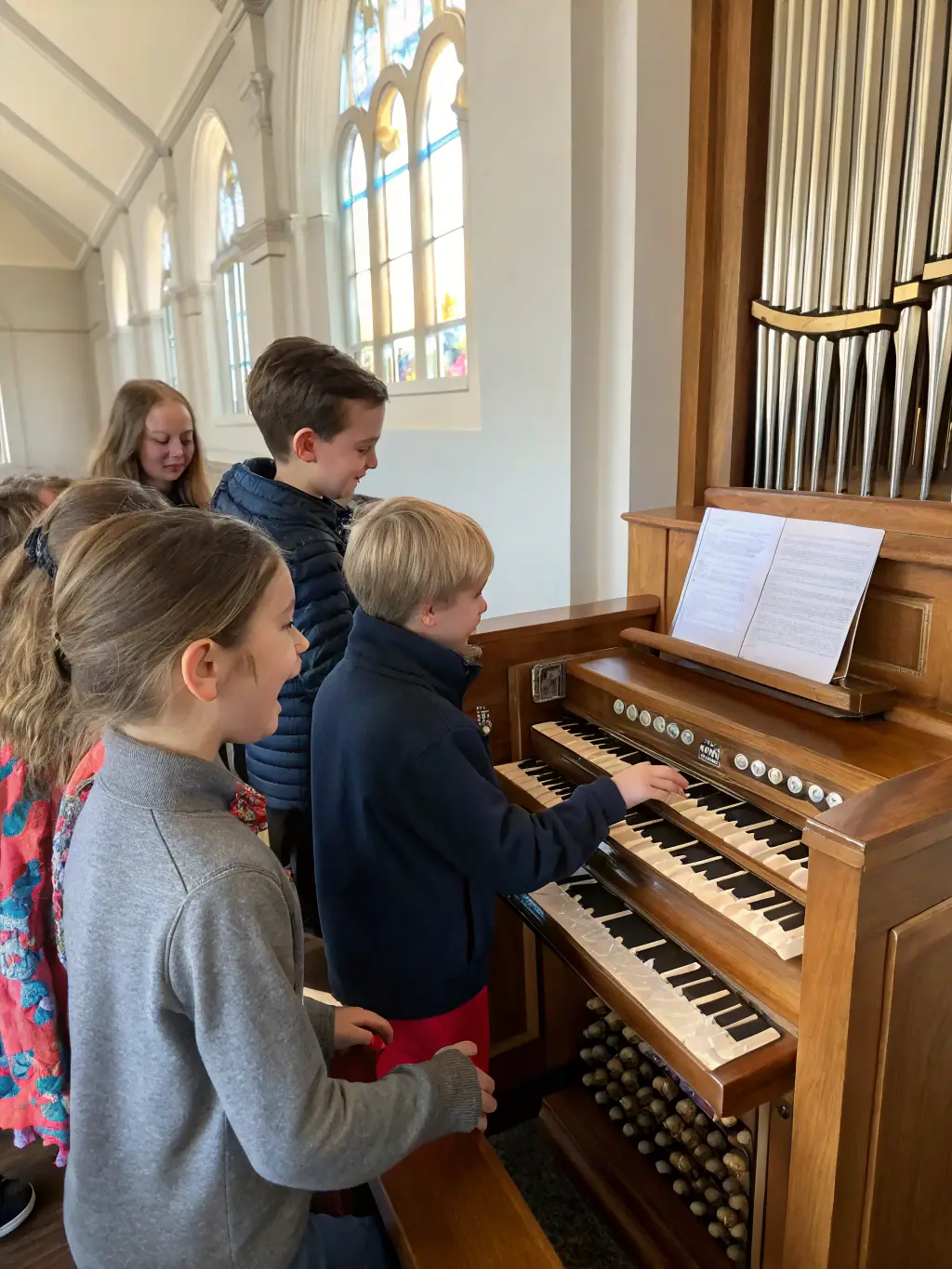 A photograph of children participating in a music education program, learning about the organ and classical music, emphasizing the importance of music education.